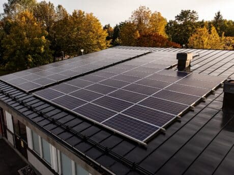 Aerial view of a house with roof solar cells, autumn forest background - drone shot