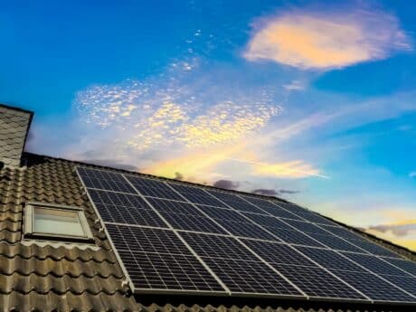 solar panels producing clean energy on a roof of a residential house during sunset