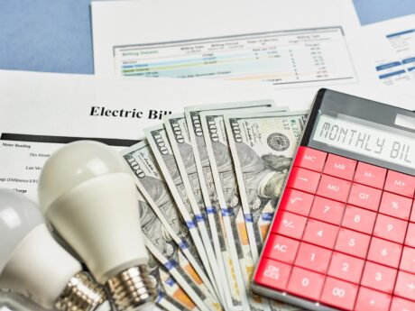 monthly utility bill represented by electric bill paper work, light bulbs, money and a caculator