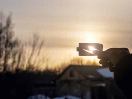 Person holding up outline of battery against sun